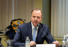 Midterms JOLTED by Israel Aid U-Turn A man in a suit speaking into a microphone.