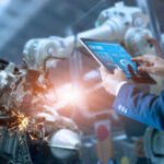 Person using a tablet to monitor robotic machinery.