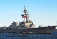Navy’s “Crappy Ship” Exposes Deep Rot naval destroyer with flags sailing on open water