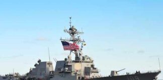 naval destroyer with flags sailing on open water