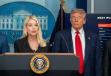 Two government officials at a press conference in front of the White House backdrop