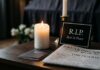 A candle and memorial card on a table with a newspaper featuring obituaries