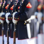 Military officers standing in formation holding rifles.