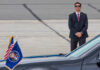 Deep State Chills Over Trump Threats A security guard in a suit stands near a presidential vehicle at an airport